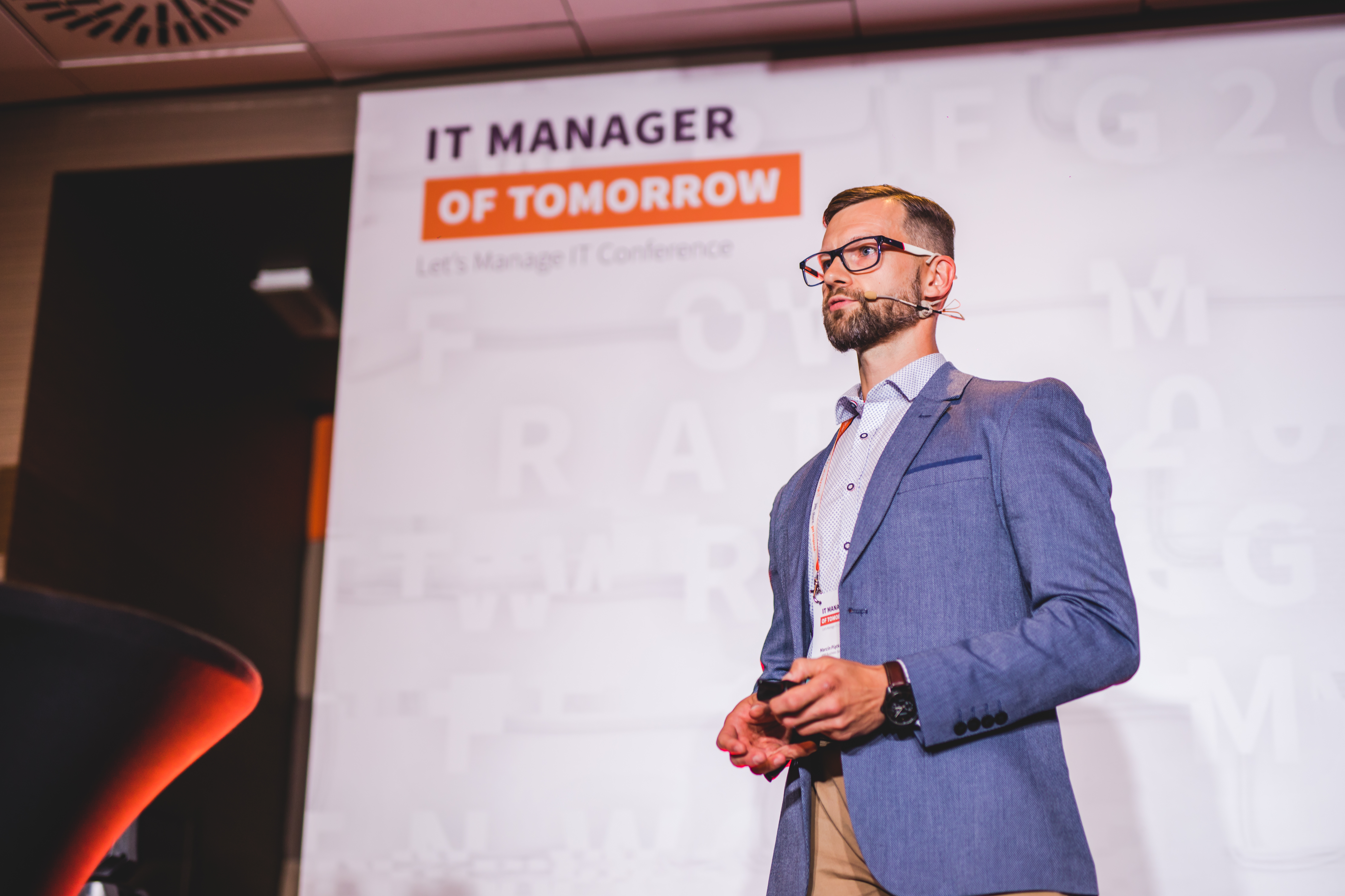 A man is delivering presentation standing on the stage.